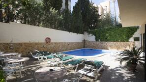 Una piscina al aire libre, tumbonas