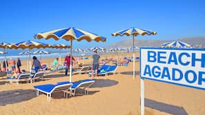 Vlak bij het strand, ligstoelen aan het strand, parasols, strandlakens