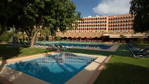 Una piscina al aire libre, sombrillas, tumbonas