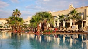 Una piscina al aire libre, sombrillas, tumbonas