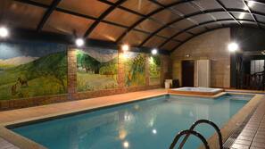 Una piscina cubierta, sombrillas, tumbonas