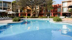 Una piscina al aire libre, sombrillas, tumbonas