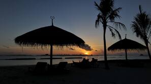 Beach nearby, white sand, beach towels, windsurfing