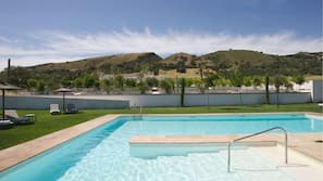 Una piscina al aire libre, sombrillas, tumbonas