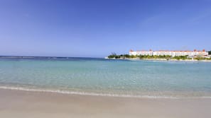 On the beach, white sand, sun loungers, beach umbrellas