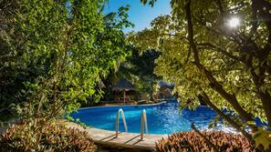 Una piscina al aire libre, sombrillas, tumbonas