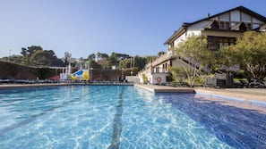 Una piscina al aire libre de temporada, sombrillas, tumbonas
