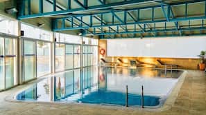 Una piscina cubierta, una piscina al aire libre, sombrillas, tumbonas