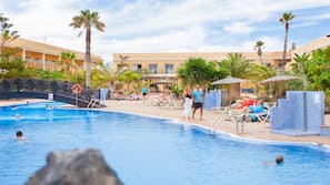 Una piscina al aire libre, sombrillas, tumbonas
