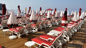 Vlak bij het strand, ligstoelen aan het strand, parasols, strandlakens