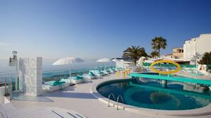 Una piscina al aire libre, sombrillas, tumbonas