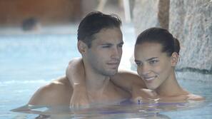 Una piscina cubierta, una piscina al aire libre, sombrillas