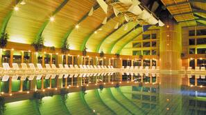 Una piscina cubierta, una piscina al aire libre, sombrillas