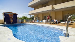 Una piscina al aire libre, tumbonas