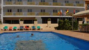 Una piscina al aire libre de temporada, sombrillas, tumbonas
