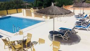 Una piscina al aire libre de temporada, sombrillas, tumbonas