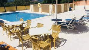 Una piscina al aire libre de temporada, sombrillas, tumbonas