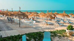 Praia particular, areia branca, espreguiçadeiras, guarda-sóis