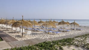 Praia particular, areia branca, espreguiçadeiras, guarda-sóis