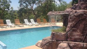 Una piscina al aire libre, una piscina con cascada, sombrillas, tumbonas