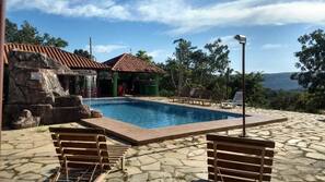 Una piscina al aire libre, una piscina con cascada, sombrillas, tumbonas