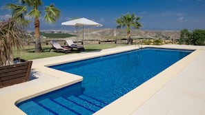 Una piscina al aire libre, sombrillas, tumbonas