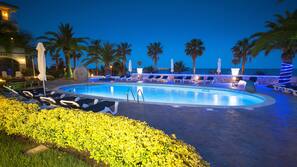 Una piscina al aire libre, sombrillas, tumbonas