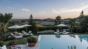 Piscina all'aperto, una piscina a sfioro, ombrelloni da piscina, lettini