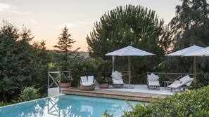 Piscina all'aperto, una piscina a sfioro, ombrelloni da piscina, lettini