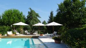 Piscina all'aperto, una piscina a sfioro, ombrelloni da piscina, lettini