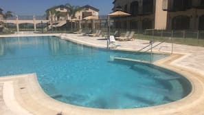 Una piscina al aire libre de temporada, sombrillas