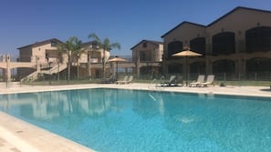 Una piscina al aire libre de temporada, sombrillas