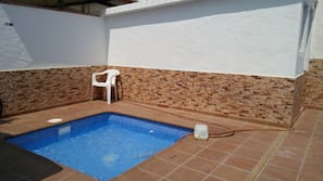 Una piscina al aire libre de temporada, sombrillas, tumbonas