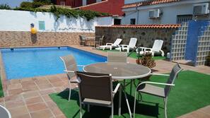 Una piscina al aire libre de temporada, sombrillas, tumbonas