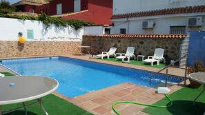 Una piscina al aire libre de temporada, sombrillas, tumbonas