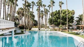 Una piscina al aire libre de temporada, sombrillas, tumbonas