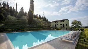 Una piscina al aire libre de temporada, sombrillas, tumbonas
