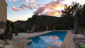 Una piscina al aire libre de temporada, sombrillas, tumbonas