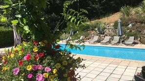 Una piscina al aire libre de temporada, sombrillas, tumbonas