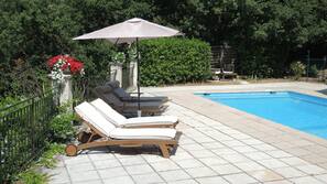 Una piscina al aire libre de temporada, sombrillas, tumbonas
