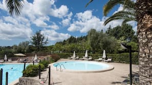 Una piscina al aire libre de temporada, sombrillas, tumbonas