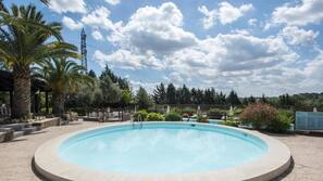 Una piscina al aire libre de temporada, sombrillas, tumbonas
