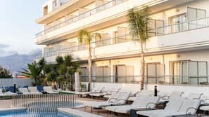 Una piscina al aire libre, sombrillas, tumbonas