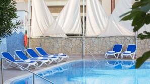 Una piscina al aire libre, sombrillas, tumbonas