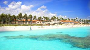 Een privéstrand, wit zand, ligstoelen aan het strand, parasols