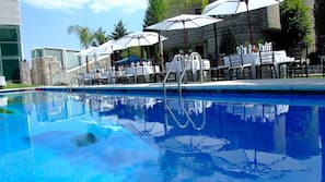Una piscina al aire libre, sombrillas, tumbonas