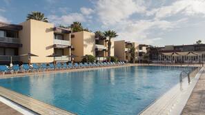 Una piscina al aire libre, sombrillas, tumbonas