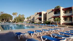 Una piscina al aire libre, sombrillas, tumbonas