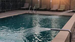 Una piscina al aire libre, sombrillas, tumbonas