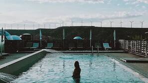 Una piscina al aire libre, sombrillas, tumbonas